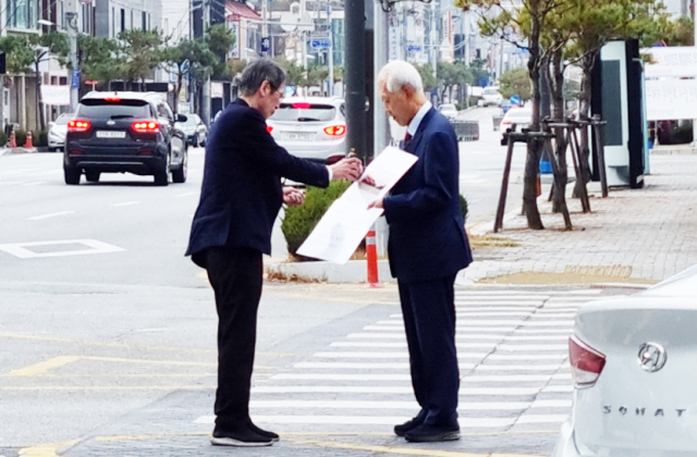 지난 14일 오전 신영국 문경대학교 총장(오른쪽)이 숭실대와 문경대의 통합을 찬성하겠다는 기존 입장을 바꿔 반대 1인시위를 벌이던 중 지나가는 시민과 악수를 나누고 있다. 독자 제공