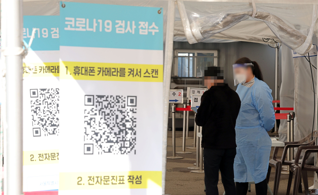 코로나19 신규 확진자 수가 4만명대로 내려온 18일 오후 서울역광장 코로나19 임시선별검사소에서 의료진이 접수를 돕고 있다. 연합뉴스