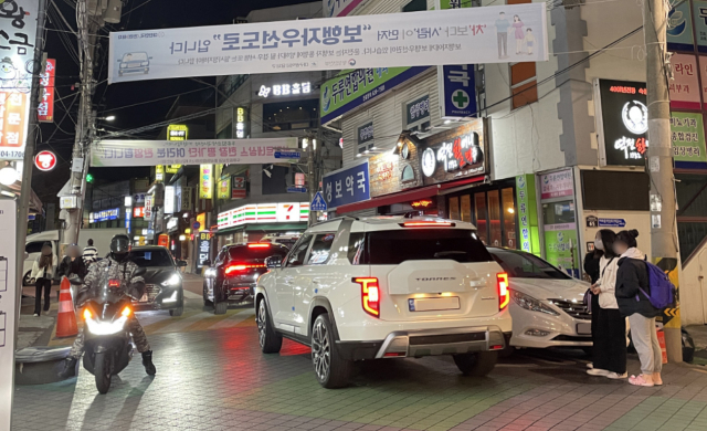 지난 18일 오후 두류 젊음의 거리 보행자 우선도로가 차량으로 붐비고 있다. 불법주차 차량 틈으로 몰린 인파 머리 위로 