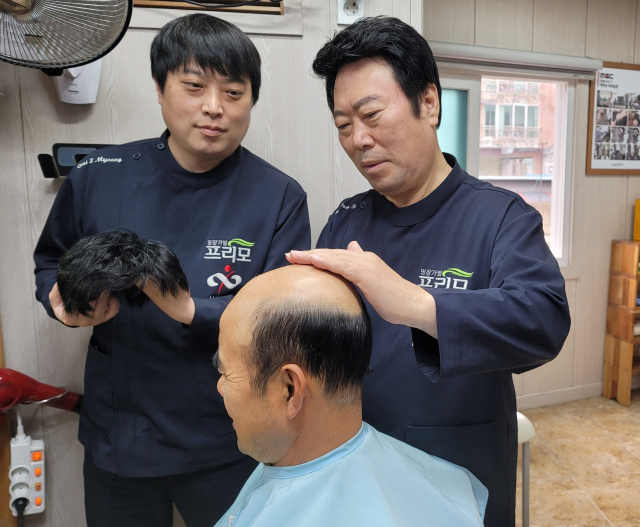 최원희 명장(왼쪽)과 최이명 부원장이 고객의 가발을 시술하는 모습. 최원프리모 제공