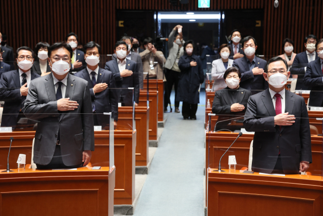 국민의힘 정진석 비상대책위원장과 주호영 원내대표가 지난 21일 오전 국회에서 열린 의원총회에서 참석 의원들과 국기에 경례하고 있다. 연합뉴스