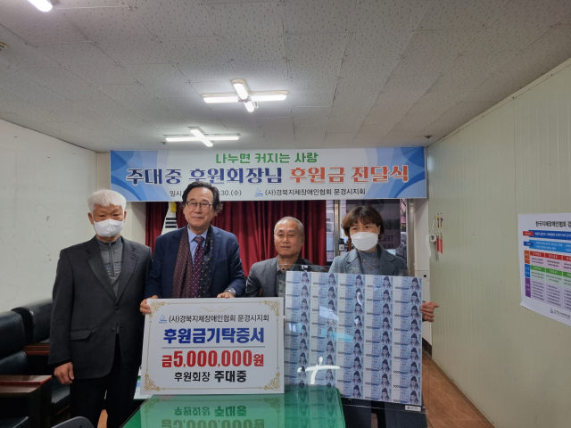 문경 장애인의 든든한 후원자 역할을 하고 있는 주대중 대구가톨릭대 겸임교수(왼쪽 두번째)가 지난달 30일 지제장애인협회 문경시지회 사무실을 찾아 후원금을 전달 한 뒤 관계자들과 기념촬영을 했다. 문경시지회 제공.