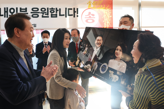 윤석열 대통령과 김검희 여사가 17일 서울 서초동 아크로비스타 사저를 찾아 주민들에게 감사 인사를 전한 뒤 주민 사진으로 만든 윤 대통령 내외 사진을 전달받고 있다. 대통령실 제공.