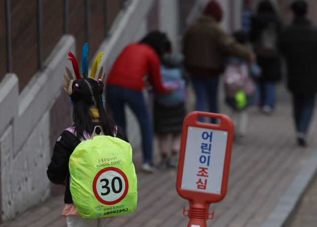 지난해 12월 강남구 언북초등학교 앞에 형광색 커버가 씌워진 가방을 멘 학생이 하교하고 있다. 연합뉴스