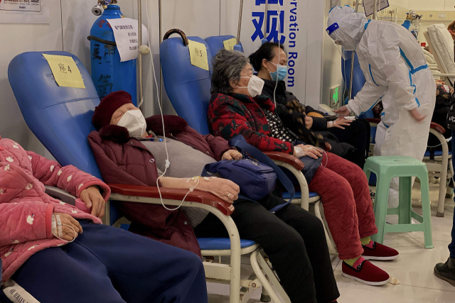 23일(현지시간) 중국 남서부 충칭시 충칭의과대학 제2부속병원에서 코로나19 환자들이 팔에 주사를 꽂은 채 줄지어 앉아있다. 최근 중국에서 코로나19 감염이 급속도로 확산하면서 방역 당국은 병상 및 의료 인력을 확보하는 데 비상이 걸렸다. 한편, 이날 마오닝 외교부 대변인은 코로나19 상황과 관련해 