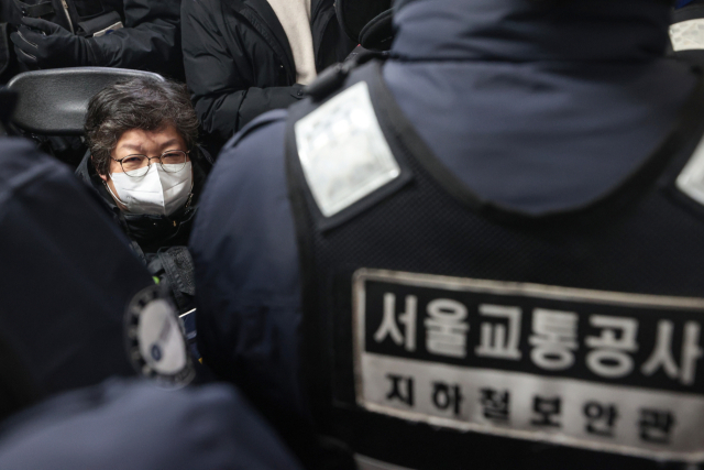 전국장애인차별철폐연대(전장연) 소속 이형숙 서울장애인자립생활센터협의회 회장이 3일 서울 4호선 동대문역사문화공원에서 지하철 탑승 시위를 벌이며 서울교통공사 직원들에 둘러싸여 있다. 연합뉴스