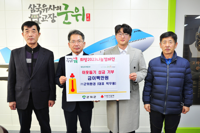 박무룡(오른쪽 두번째) 군위환경 대표가 김진열(왼쪽 두번째) 군위군수에게 이웃돕기 성금을 기부하고, 기념 사진을 촬영하고 있다. 군위군 제공