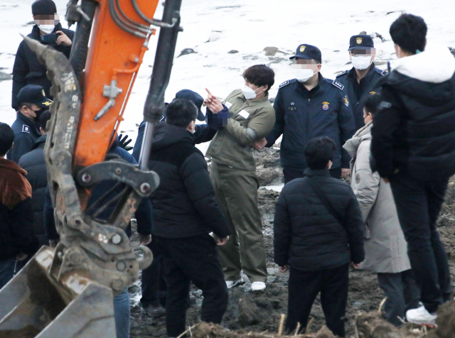 택시 기사와 동거녀를 살해한 혐의로 구속된 이기영이 6일 오후 경기도 파주 공릉천변에서 검찰 관계자들에게 시신을 매장했다고 진술한 부근을 손으로 가리키고 있다. 연합뉴스