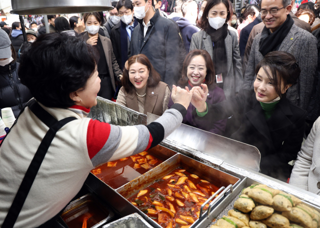 김건희 여사가 11일 대구 서문시장에서 만두 등 음식을 맛본 뒤 재방문을 약속하며 상인과 새끼손가락을 걸고 있다. 연합뉴스