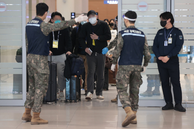 9일 오전 인천국제공항 제2여객터미널에서 방역 관계자들이 중국발 입국자들을 코로나19 검사센터로 인솔하고 있다. 이날 중앙방역대책본부에 따르면 지난 8일 기준 중국발 입국자 934명 중 단기체류 외국인 180명이 유전자증폭 검사를 받아 3.9％에 해당하는 7명이 양성 판정을 받았다. 연합뉴스
