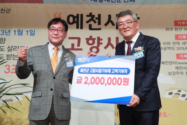 윤태전(왼쪽) 예천군재경면민회장이 김학동 예천군수에게 고향사랑기부금 200만원을 전달하고 있다. 예천군 제공
