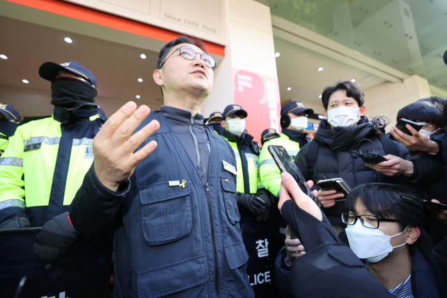 18일 오전 국정원 압수수색이 이루어지고 있는 서울 중구 전국민주노동조합총연맹(민주노총) 서울 사무실 앞에서 한상진 민주노총 대변인이 브리핑하고 있다. 연합뉴스