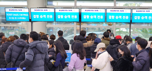 폭설과 한파가 제주를 덮칠 것으로 예상되는 가운데 23일 오후 제주공항 내 대한항공 대기 카운터에 탑승권을 구하려는 승객들이 줄을 서 있다. 대한항공은 24일 제주공항 출도착 전편을 결항 조치했다. 연합뉴스