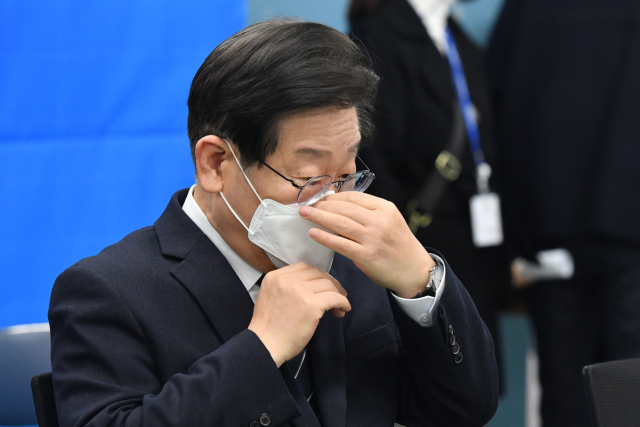 더불어민주당 이재명 대표가 28일 학교 급식실 노동자 폐암 진단과 관련, 서울 은평구 수색초등학교를 방문해 급식 노동자들과의 간담회에서 마스크를 고쳐 쓰고 있다. 연합뉴스
