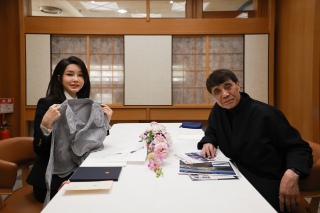 김건희 여사가 17일 일본 도쿄 한 식당에서 세계적인 건축가 안도 다다오와 오찬을 하며 이세이미야케 옷을 선물받고 있다. 연합뉴스