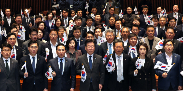 더불어민주당 이재명 대표와 의원들이 16일 오후 서울 여의도 국회에서 열린 의원총회에서 태극기를 들고