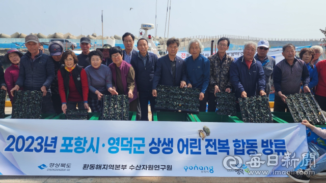 포항시와 영덕군 어촌계원 등이 29일 포항 송라면 지경리~영덕군 남정면 부경리 경계 지점에서 어린 전복 10만 마리를 합동 방류하기에 앞서 기념촬영을 하고 있다. 포항시 제공