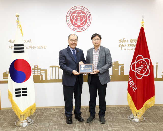 홍원화 경북대 총장이 대학 발전과 인재 양성을 위해 발전기금을 출연한 손인준 신소재공학부 교수에게 발전기금 감사패를 전하고 있다. 경북대 제공