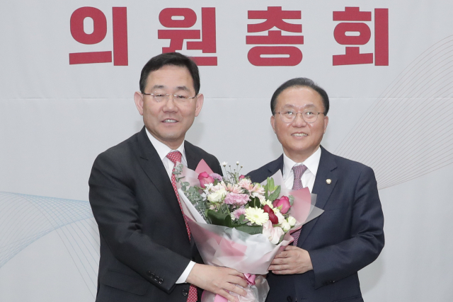 국민의힘 윤재옥 신임 원내대표(오른쪽)가 7일 오전 국회에서 열린 국민의힘 원내대표 선출을 위한 의원총회에서 당선 확정 후 주호영 전 원내대표로부터 꽃다발을 받고 있다. 연합뉴스