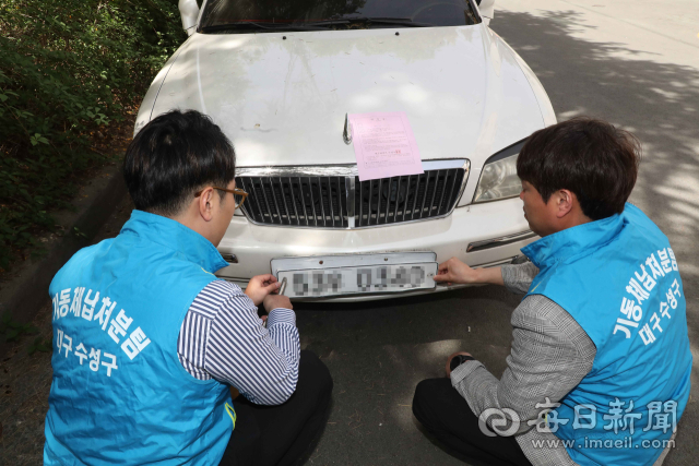대구 수성구와 경산시가 합동으로 자동차세 체납 차량에 대한 번호판 영치에 나선 가운데 12일 수성구 신매동 주택가에서 수성구청 세무2과 38기동팀이 체납 차량 번호판을 떼고 있다. 합동 번호판 영치 대상은 자동차세 3회 이상 체납 차량이다. 매일신문 DB.