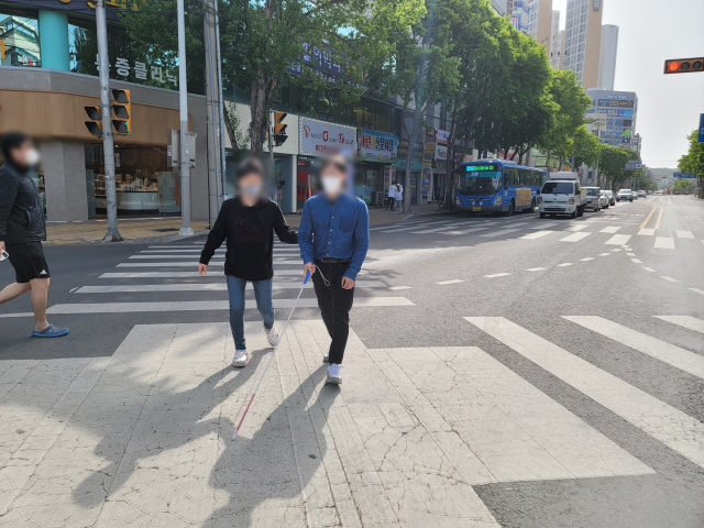 지난 17일 달서구 본리초 인근 사거리에서 시각장애인 최지현(29)씨가 근로지원인의 도움을 받아 아슬아슬하게 대각선 횡단보도를 건너고 있다. 박성현 기자