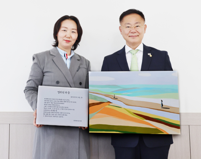김재욱(오른쪽) 칠곡군수가 천재 동화작가 전이수 군의 작품을 최보영 칠곡장애인부모회장에게 전달하고 있다. 칠곡군 제공