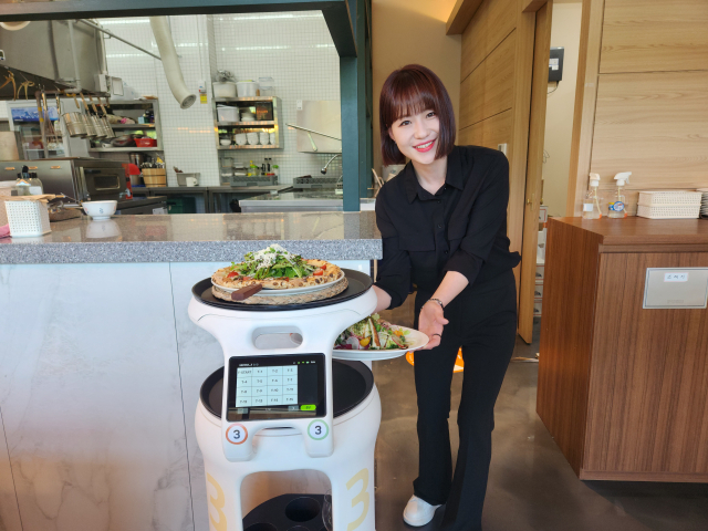 27일 오전 11시 대구 달성군 유가읍 나폴리언덕에서 점원이 조리된 음식을 AI서빙로봇에 싣고 있다. 이통원 기자. tong@imaeil.com