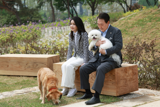 2023년 5월 4일 윤석열 전 대통령과 부인 김건희 여사가 서울 용산 대통령실의 앞마당에 조성된 용산 어린이정원 개방 기념식수를 마친 뒤 써니와 은퇴안내견 새롬이(왼쪽)와 휴식을 취하고 있다. 연합뉴스