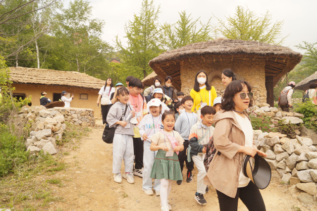 '2023 한티가는 길' 걷기 행사에 참가한 참가자들이 억새마을 초가집 길을 걷고 있다. 전병용 기자