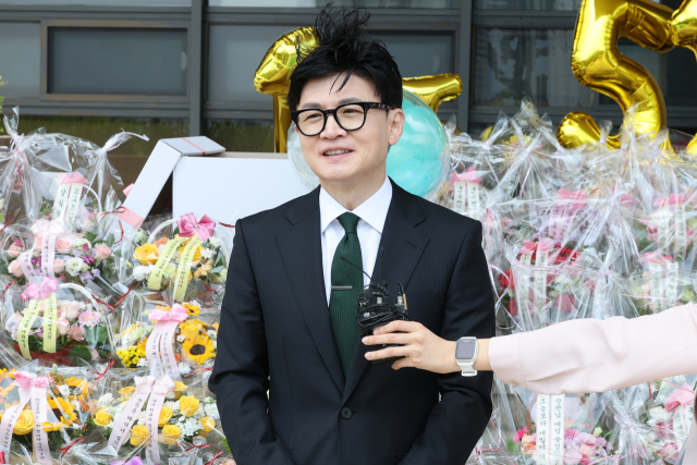 한동훈 법무부 장관이 취임 1년을 맞은 17일 오전 정부과천청사 법무부로 출근하며 소회를 묻는 기자의 질문에 답하고 있다. 이날 법무부 앞 계단에는 지지자들이 보낸 축하 꽃다발이 수북이 놓여 있었다. 연합뉴스