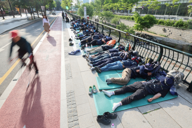 17일 오전 출근시간대 시민들이 서울 중구 청계광장에서 전날 밤 총파업 결의대회 후 노숙하고 있는 민주노총 건설노조원들을 지나치고 있다. 이날 건설노조를 포함한 민주노총은 오후 2시 숭례문 앞에 집결해 결의대회를 열고 삼각지역까지 행진할 예정이다. 연합뉴스