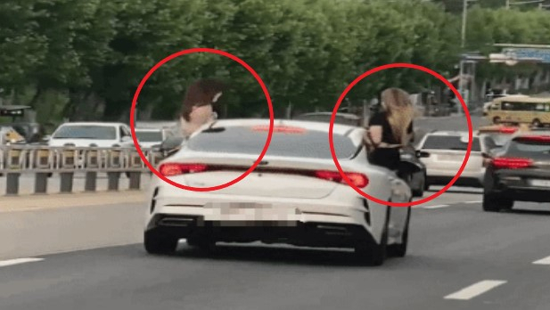 창문에 여성 2명이 겉터 앉은 채로 달리고 있는 승용차. 연합뉴스