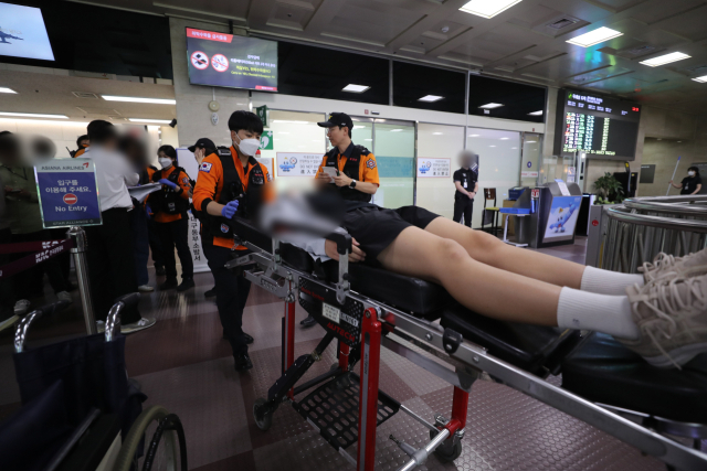 지난 5월 26일 제주를 출발해 대구로 향하던 아시아나 항공기에서 비행 중 문이 열리는 사고가 발생했다. 당시 비행기에 탑승했던 초·중학생 제주도선수단 가운데 대구공항 도착 후 고통을 호소하는 선수들을 119구조대가 들것을 이용해 구급차로 옮기고 있는 모습. 연합뉴스