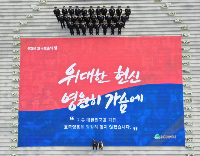 현충일을 하루 앞둔 5일 오후 대구 남구 충혼탑에 호국 영웅들을 기리는 대형 현수막이 게시된 가운데 대구시 경찰들이 기념 촬영을 하고 있다. 연합뉴스