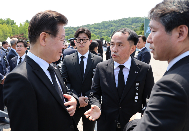 이재명 더불어민주당 대표(왼쪽)가 6일 서울 동작구 국립서울현충원에서 열린 제68회 현충일 추념식장에서 추념식이 끝난 뒤 최원일 전 천안함장(가운데)으로부터 항의를 받고 있다. 연합뉴스