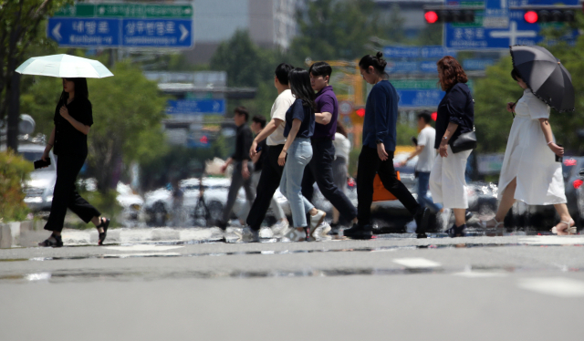 15일 오후 광주 서구 내방로에서 시민들이 뜨거운 햇볕에 달아올라 아지랑이가 피어오르는 도로를 건너고 있다. 연합뉴스