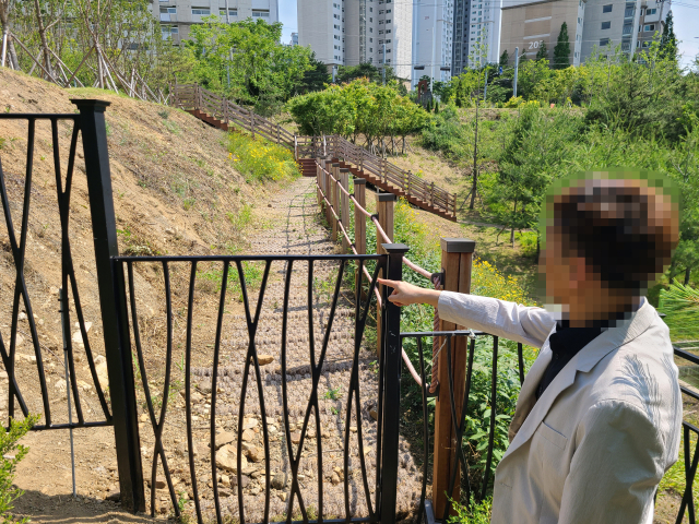 지난 23일 구미 호반베르디움 아파트 입주민이 단지 외곽에 설치된 철제 울타리를 손으로 가르키고 있다. 단지 주변에 구미시가 13억원을 들여 도시숲을 조성했지만 시행사가 쪽문 설치를 반대하면서 입주민들이 거의 이용하지 못하고 있다. 조규덕 기자