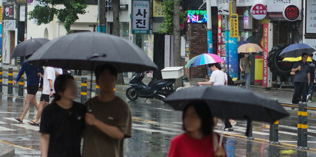 경남도가 장마철에 접어든 25일 오후 경남 창원시 마산합포구 한 거리에서 시민이 우산을 쓴 채 걷고 있다. 연합뉴스