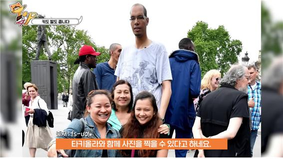 전 세계 키 2위, 발 크기 1위인 타키올라가 자신을 만나러 온 관광객들과 함께 기념사진을 찍고 있다. 출처=fs-uol