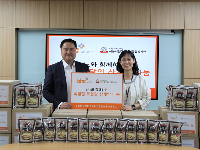 bhc그룹 임인엽 이사(좌측)가 서울시립 강동노인종합복지관 성미선 관장(우측)에게 삼계탕을 전달한 후 기념촬영을 하고 있다.