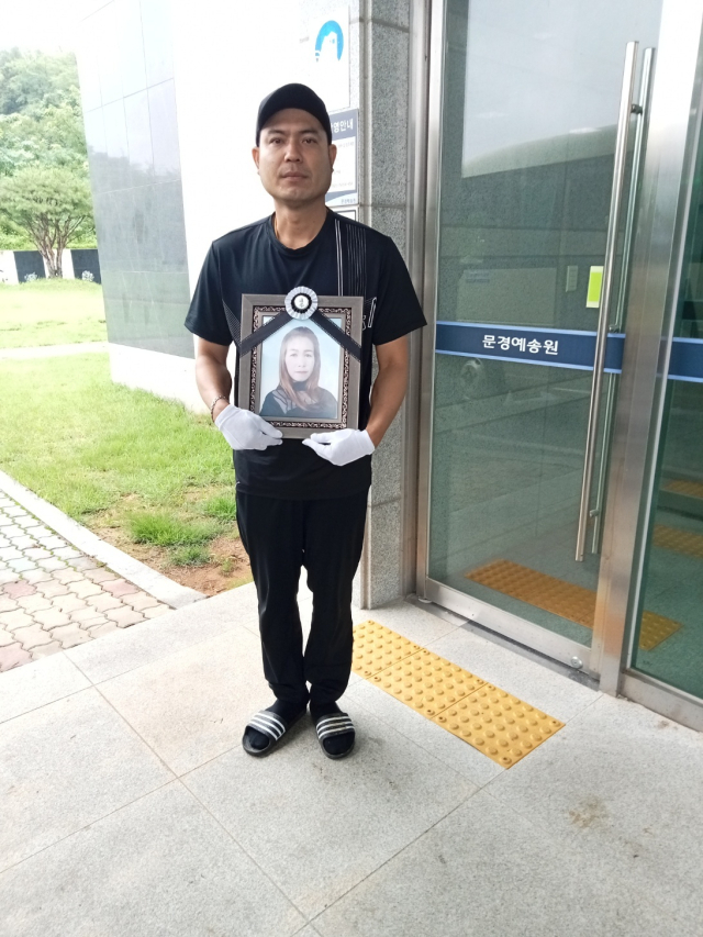 18일 오후 집중호우에 문경에서 희생된 외국인 띠얍(32) 씨의 영정을 남편이 안고 있다. 문경시 제공