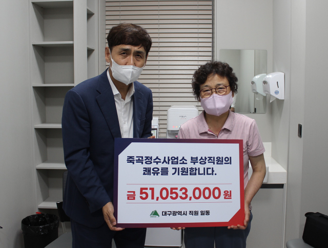 지난 18일 이재홍 대구시 행정국장(왼쪽)이 죽곡정수장 부상 공무원 김성배 씨 어머니에게 직원들이 모은 성금을 전달했다. 대구시 제공
