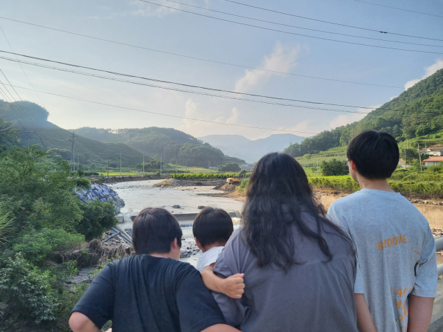 지난 21일 조선영(가명·35) 씨가 세 아들과 함께 집 근처 수해복구 공사 현장을 바라보고 있다. (왼쪽부터)둘째 오지성(가명·12) 군, 막내 금성(가명·5)이, 선영 씨, 첫째 오수성(가명·15). 윤정훈 기자