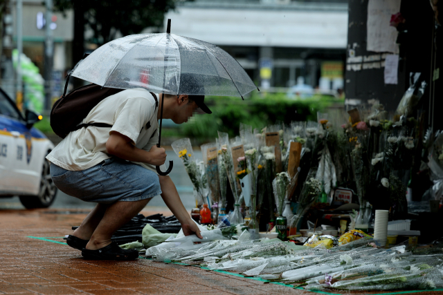23일 오전 서울 관악구 신림역 인근 상가 골목에 마련된 흉기난동 사건으로 숨진 20대 남성을 추모하는 공간을 찾은 시민이 고인의 명복을 빌고 있다. 범인 조모 씨는 이날 오후 서울중앙지법에서 구속 전 피의자 심문을 받을 예정이다. 연합뉴스