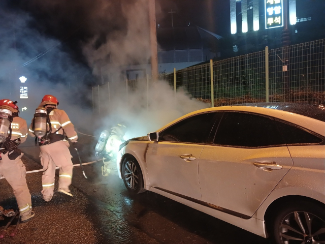 지난 24일 오후 포항시 북구 흥해읍 대련리 한 도로를 달리던 승용차량에서 발생한 화재를 소방대원들이 진화하고 있다. 포항북부소방서 제공.