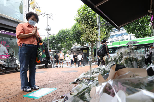 25일 오후 서울 관악구 신림역 인근 상가 골목에 마련된 흉기난동 사건으로 숨진 20대 남성 피해자 A씨를 위한 추모 공간에서 한 시민이 기도하고 있다. 한편 행인에게 흉기를 휘둘러 4명의 사상자를 낸 조모 씨에 대한 신상 공개 여부는 오는 26일 결정된다. 연합뉴스