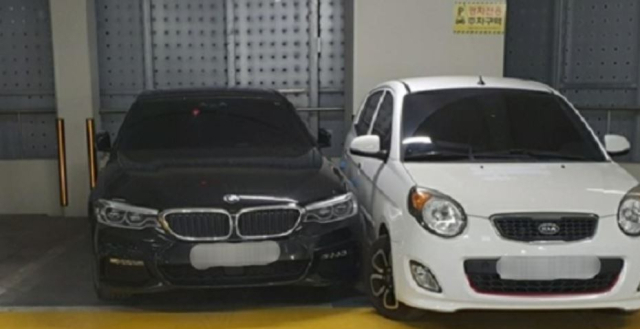 주차선을 넘어온 BMW 차량 옆에 경차가 주차돼 있다. BMW 차주는 차를 못 빼 경찰의 도움을 받았다. 연합뉴스