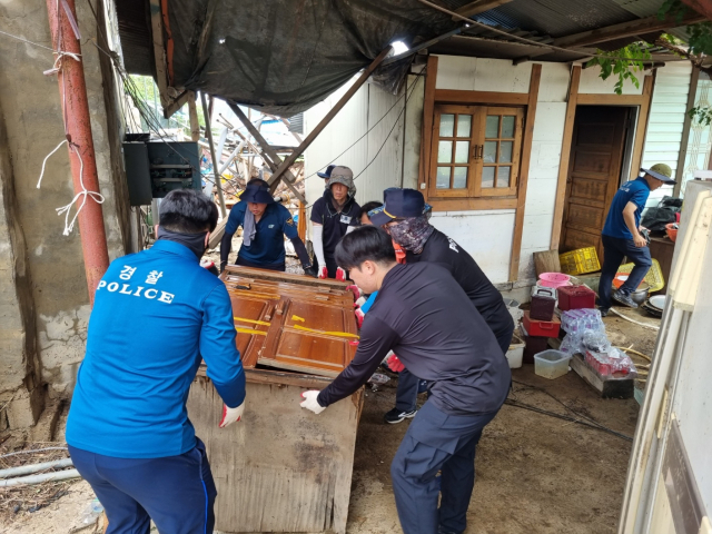 이성균 경북 군위경찰서장과 직원들이 휴일을 반납하고 태풍 피해를 입은 부계면의 농가를 찾아 가재도구를 정리하고 있다. 군위경찰서 제공