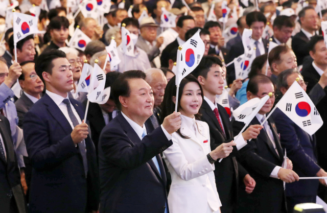 윤석열 대통령과 김건희 여사가 15일 서울 서대문구 이화여대 대강당에서 열린 제78주년 광복절 경축식에서 만세삼창을 한 뒤 태극기를 흔들고 있다. 연합뉴스