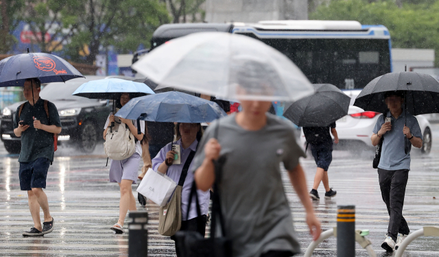 서울 전역에 호우주의보가 발효 중인 지난달 23일 오전 서울 광화문광장에서 시민들이 우산을 쓴 채 걸어가고 있다. 연합뉴스